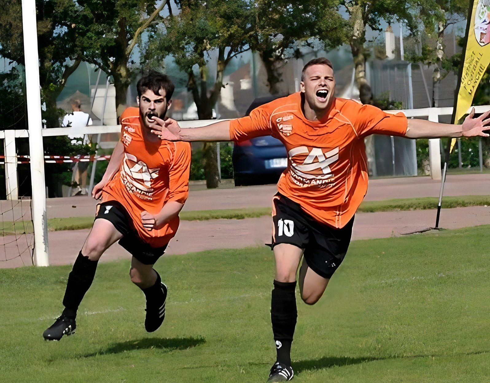 Deux joueurs de l'ASS Urville-Nacqueville en maillot orange courent bras ouverts pour célébrer un but